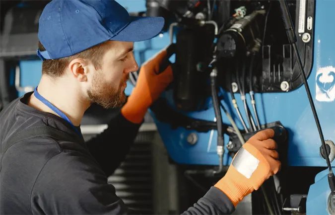 Worker repairing machine components with gloves.